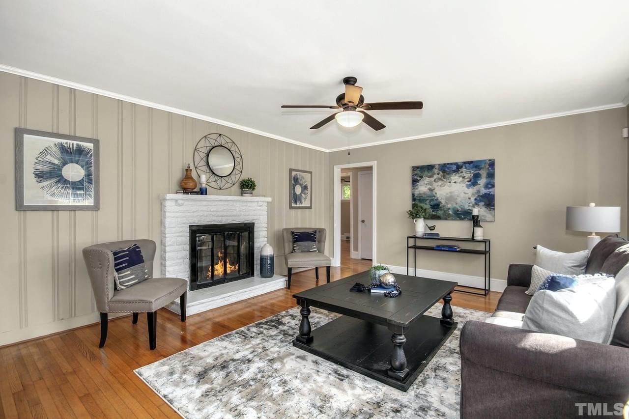 A light gray living room with accent wall, wood floor, gray furniture, white brick fireplace